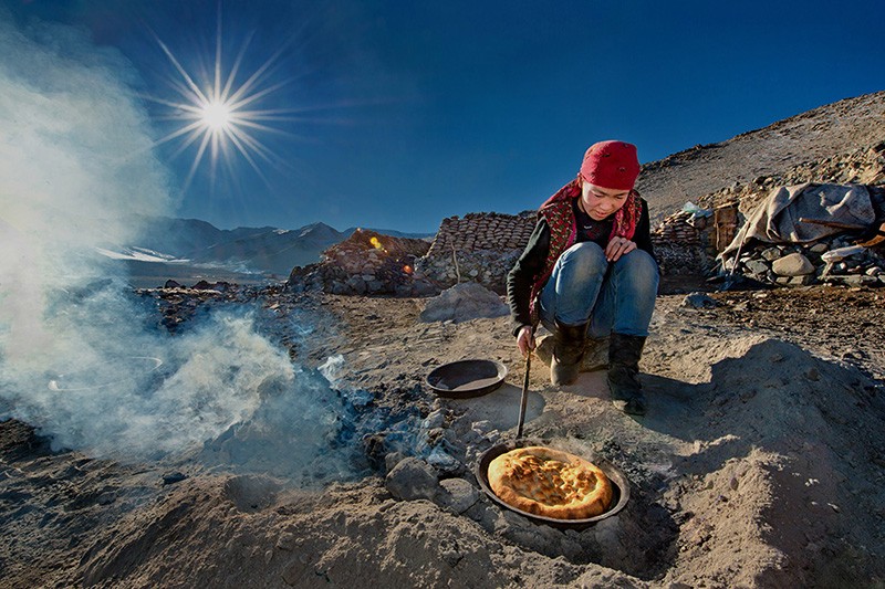 4.在冬牧场，妇女用羊粪炭火烤制馕饼。.jpg