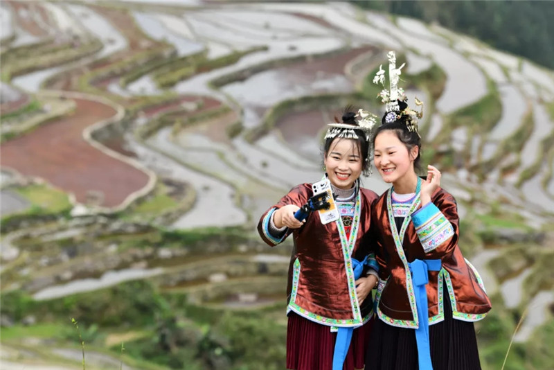 4. 1994年出生的吴贤艳是贵州省从江县一名地道的侗族女孩，2017年大学旅游管理专业毕业的她选择回到月亮山区，通过社会公开招考成为从江县加榜梯田景区管理委员会的一名工作人员。图为吴贤艳（左）与村里的大一女生梁琼英在直播推介加榜梯田风光（4月19日摄）。　新华社记者 杨文斌 摄.webp.jpg