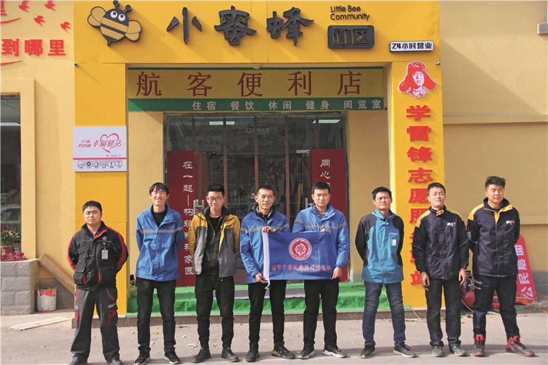 快递员在“小蜜蜂社区”前，手持贺兰县民族团结进步LOGO，为创建加油打气_副本.jpg
